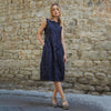 Model wearing a navy blue and white striped tapered dress with a split neckline. Her right is placed inside one of the included pockets.