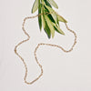 Gold chain necklace on a light background with green leaves