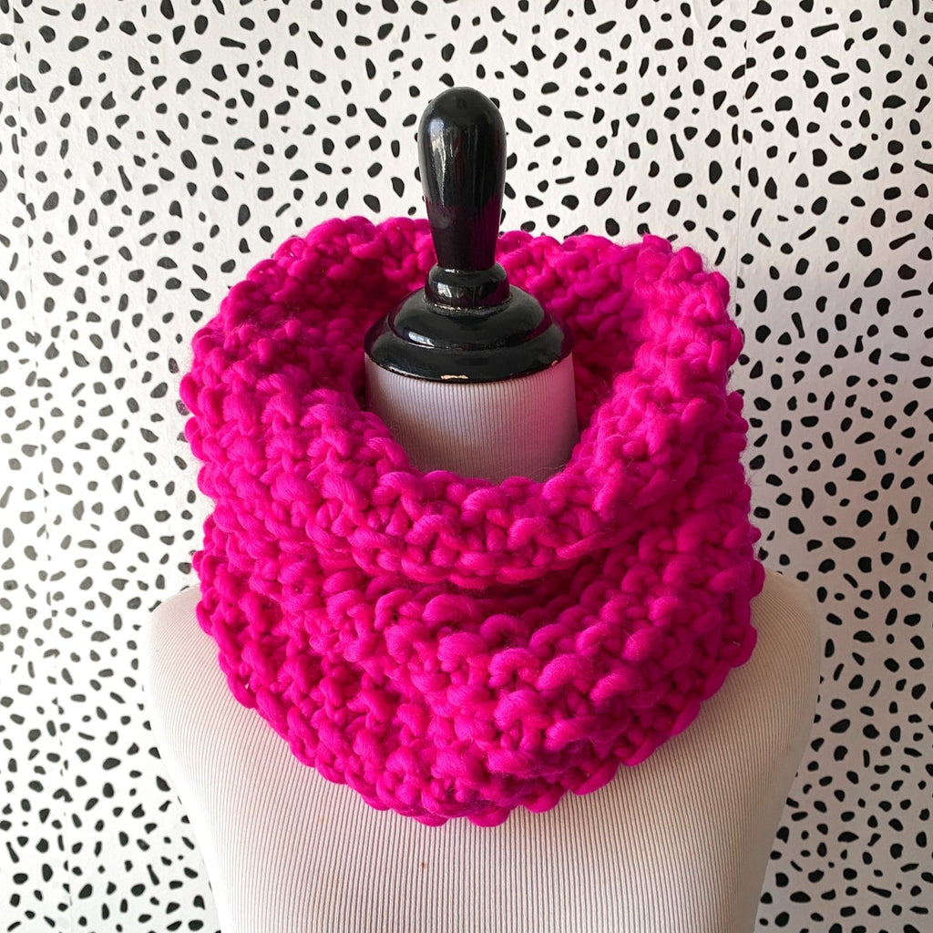 Hot pink knitted cowl on a mannequin against a polka dot background