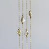 Delicate gold necklace with pearls on a light gray background