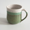 Ceramic mug with green speckly glaze covering 3/4 of the mug from the bottom, and white glaze with speckles covering the remaining top lip.