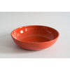Ceramic pasta bowl in coral color with small black speckles.