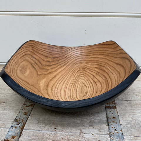 Angled wooden salad bowl with a blackened exterior finish