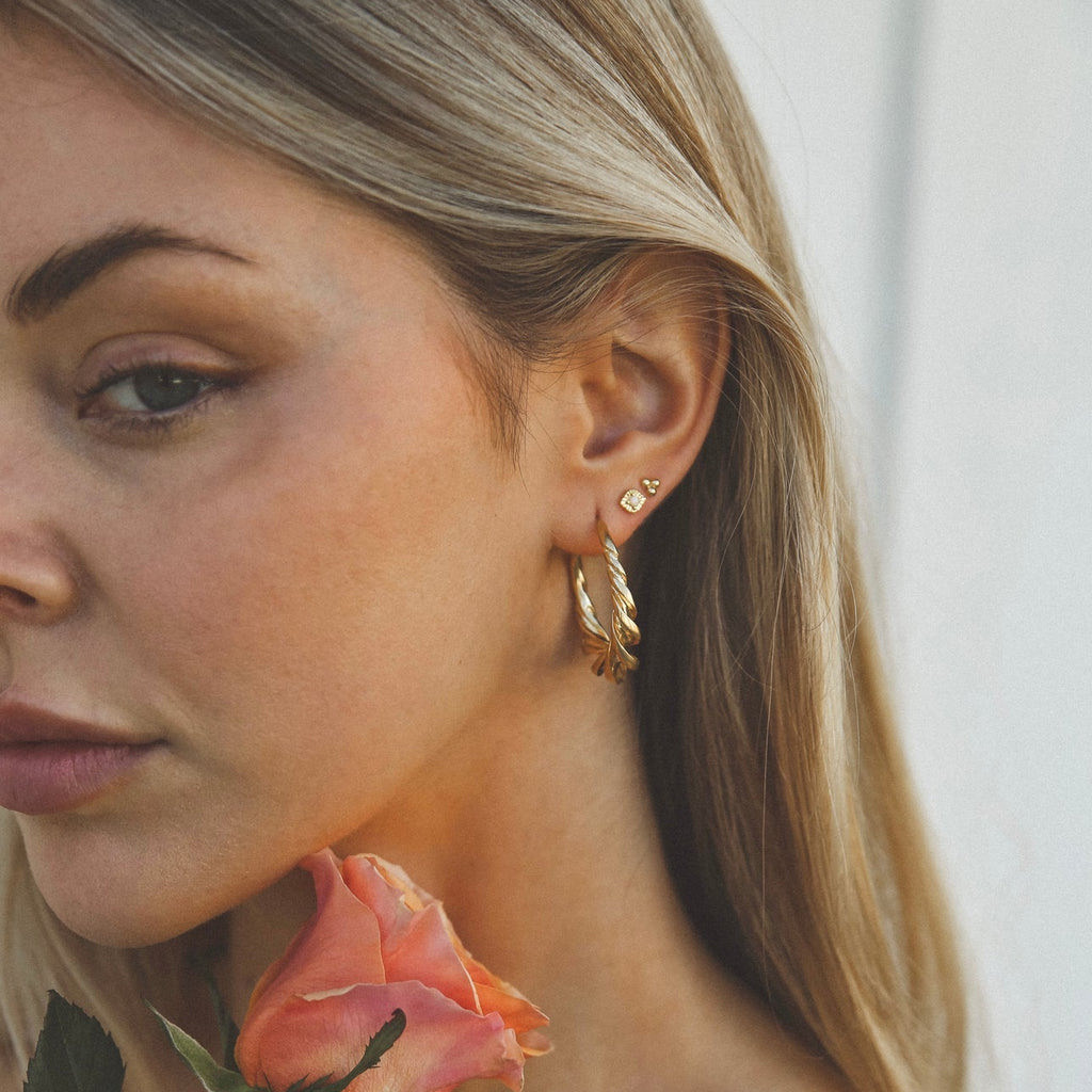 Woman wearing gold hoop earrings with a blurred background