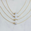 Three gold necklaces with variously shaped pearls on a light gray background
