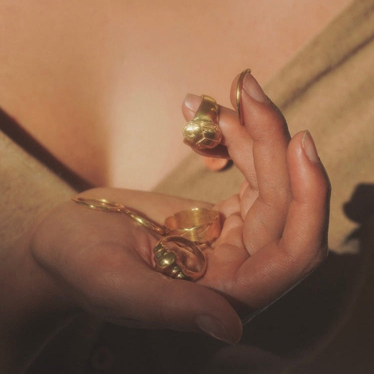Hand holding a gold ring with a blurred background