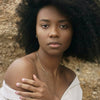 Woman with an afro wearing a white top against a natural background