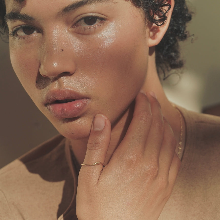 Close-up of a person wearing a gold ring on their finger.