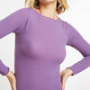 Woman wearing a purple long-sleeve top against a white background