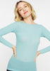 Woman wearing a light blue long-sleeve top against a white background