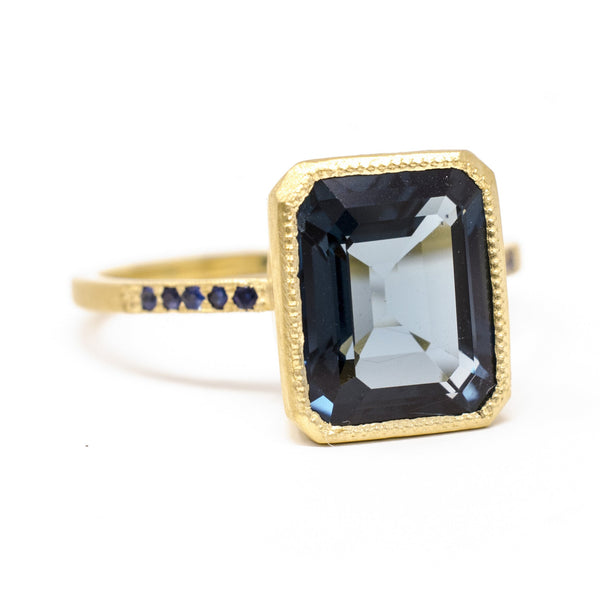 Gold ring with a large blue gemstone on a white background
