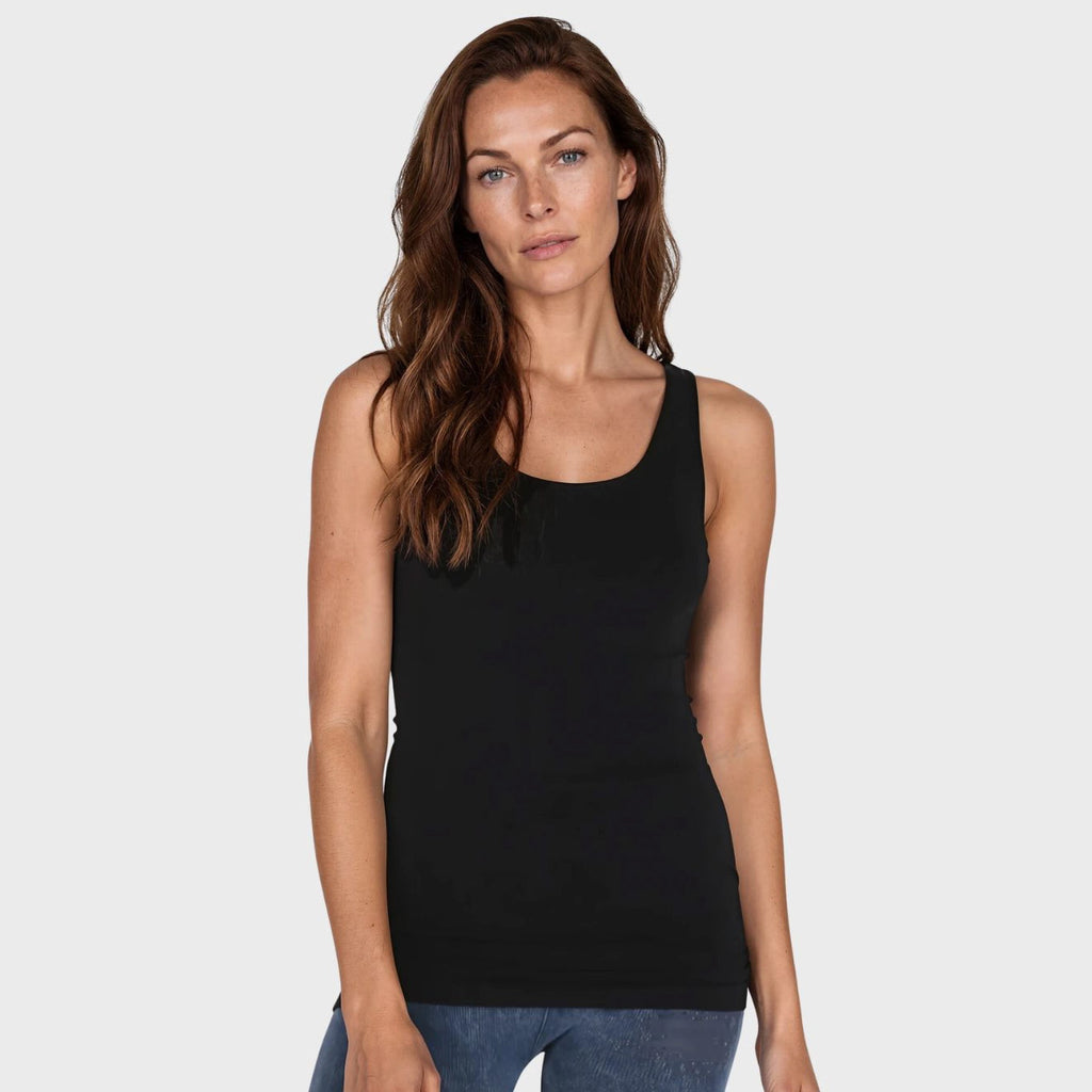 Woman wearing a black tank top against a plain background
