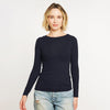 Woman wearing a black long-sleeve top and jeans on a plain background