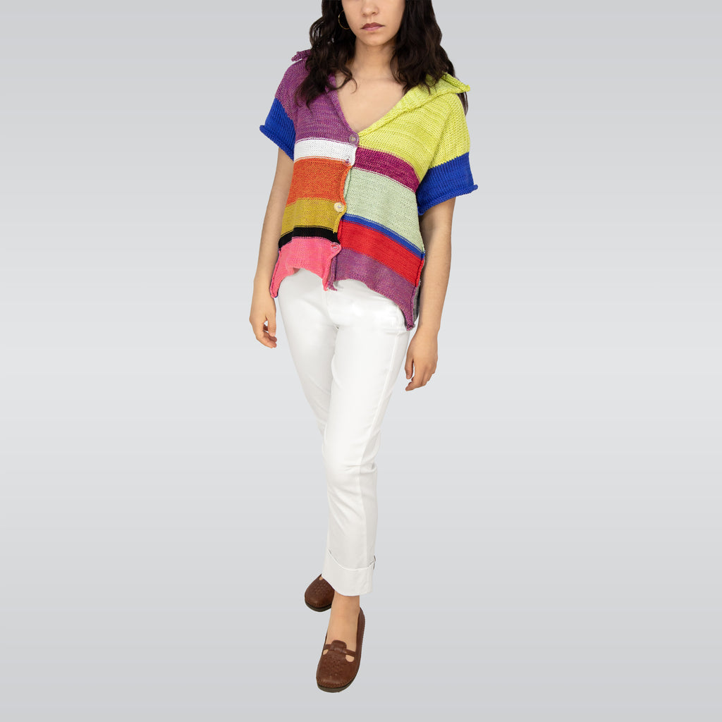 Person wearing a colorful striped sweater and white pants on a plain background