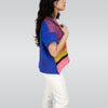Person wearing a colorful striped sweater and white pants on a plain background