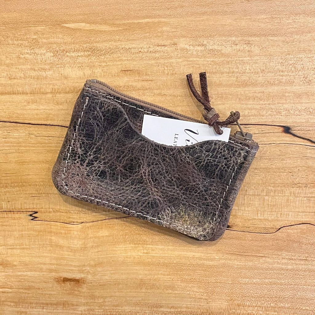 Brown leather pouch with a textured surface on a wooden background