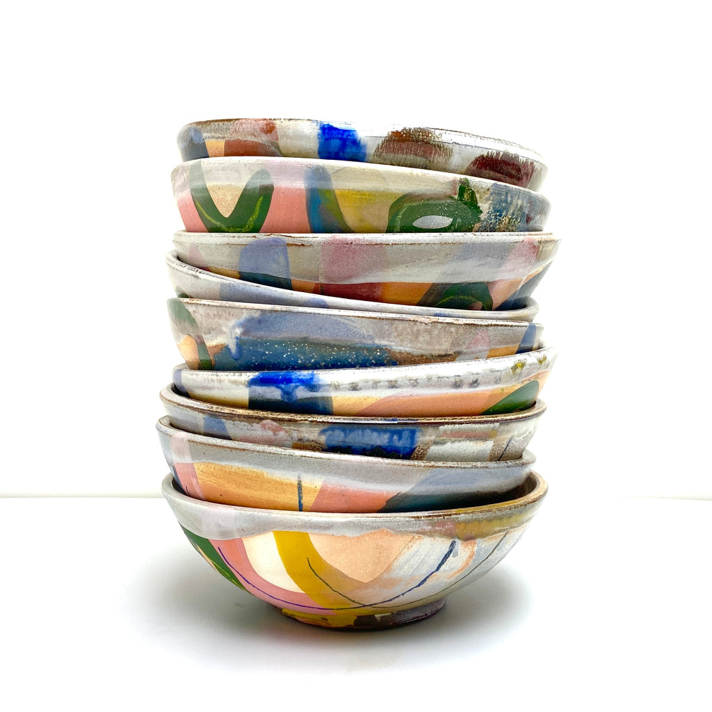 Stack of colorful ceramic bowls on a white background