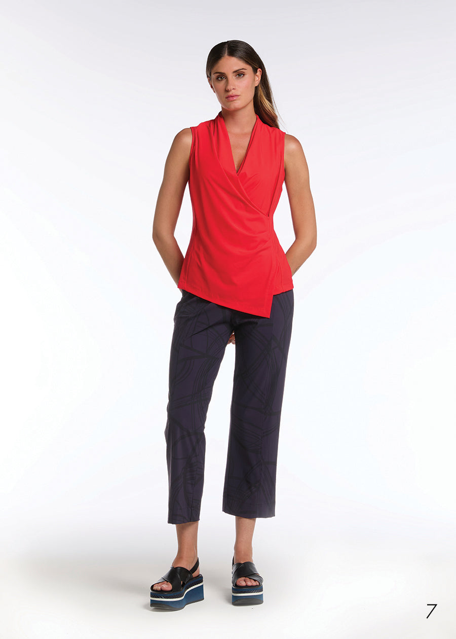 Woman wearing a red sleeveless top and dark pants on a white background