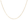 A delicate gold-fill layering necklace chain laid out on a plain background.