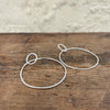 Silver hoop earrings on a wooden surface with a neutral background