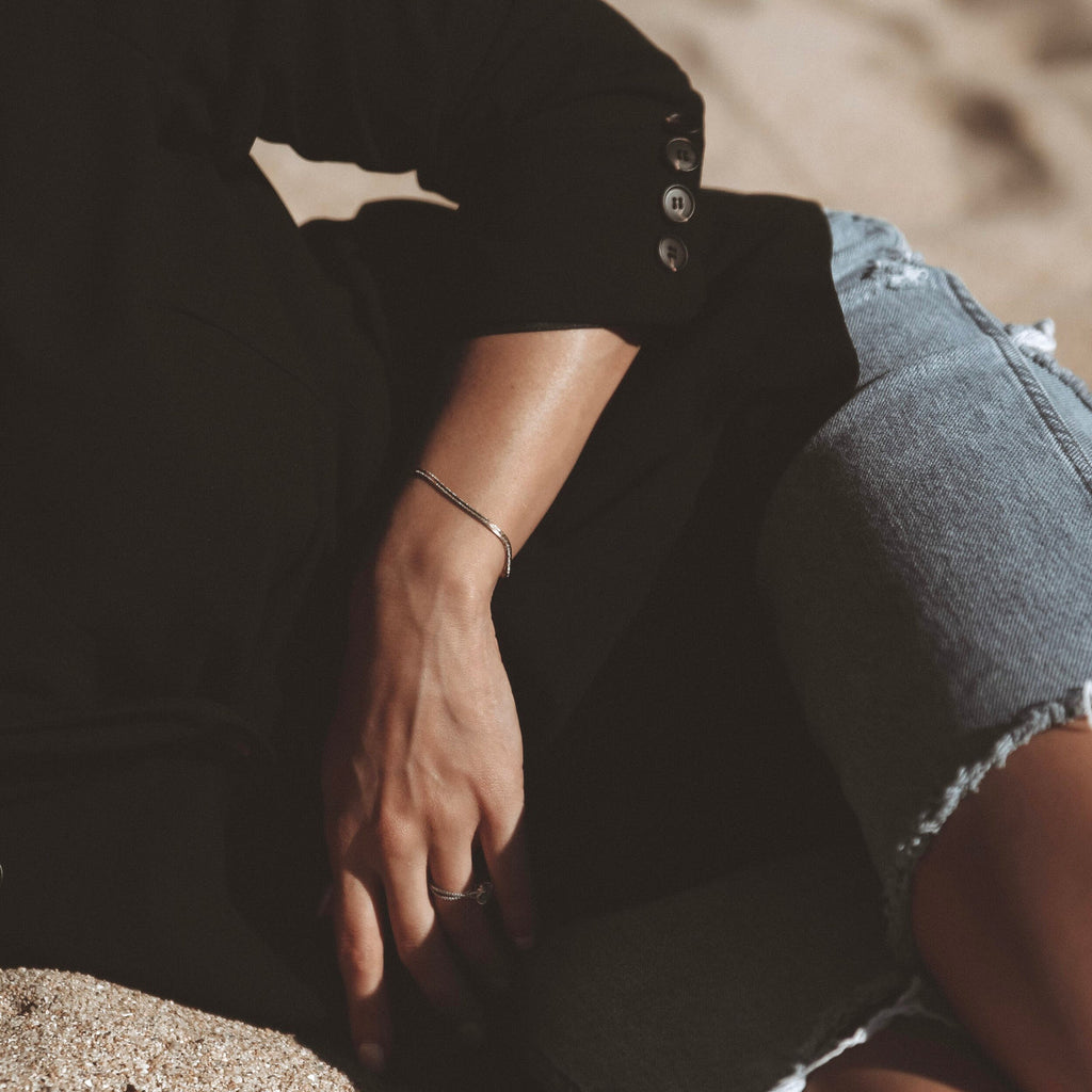 Person wearing a black shirt and denim shorts sitting on sand