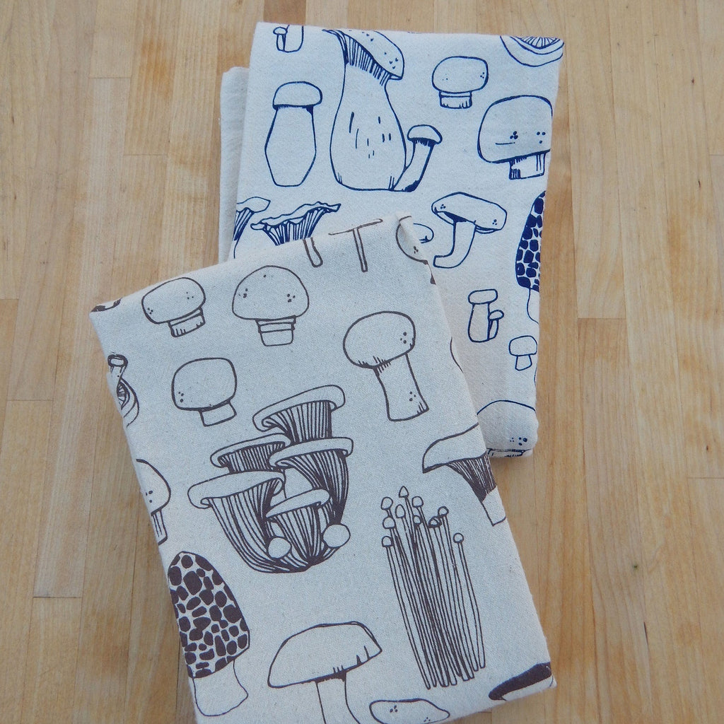 Two fabric napkins with mushroom pattern on a wooden surface