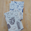Two fabric napkins with mushroom pattern on a wooden surface