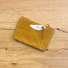 Mustard leather cardholder on a wooden surface