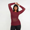 Woman wearing a burgundy long-sleeve top on a white background