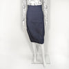 Mannequin wearing an over the knee dark navy pencil skirt with a front trifold seam-line. It is paired with a white long sleeve top designed with stenciled faces.