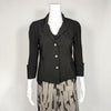 mannequin wearing a black 3/4, cuffed and collared jacket with three metal buttons down the center. It is paired with a patterned black and grey pant.