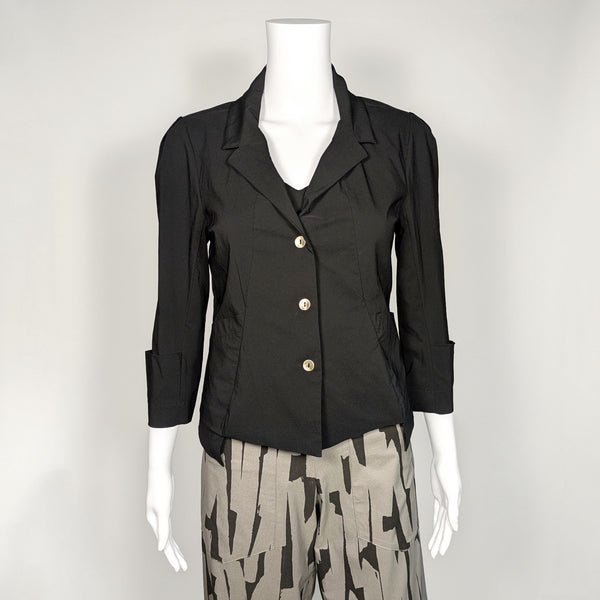 mannequin wearing a black 3/4, cuffed and collared jacket with three metal buttons down the center. It is paired with a patterned black and grey pant.