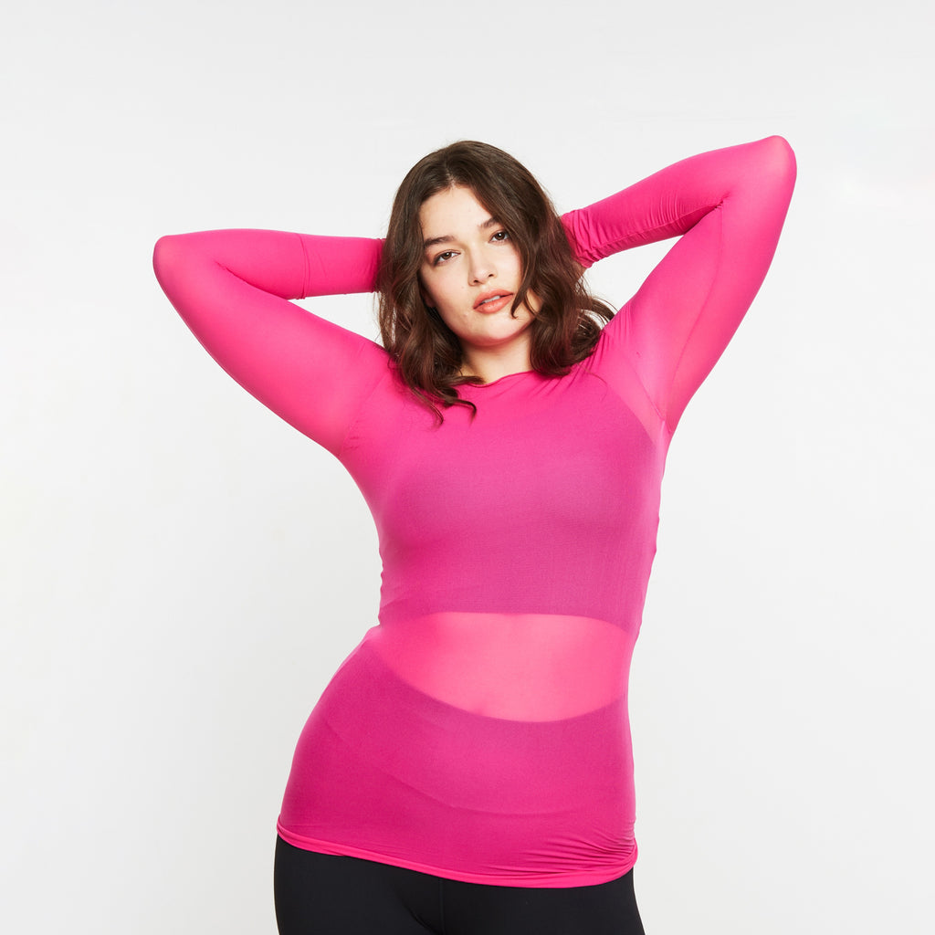Woman wearing a bright pink long-sleeve top on a white background