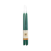 Two dark green taper candles wrapped together with a cream paper band featuring a bee logo and a gold patterned accent, set against a plain white background.