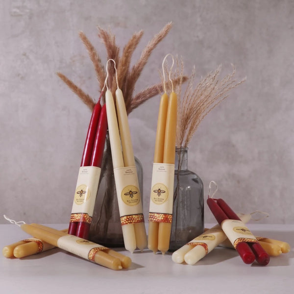 Set of beeswax candles with decorative labels on a neutral background