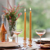 Dining table setting with candles, glasses, and a bottle of wine.