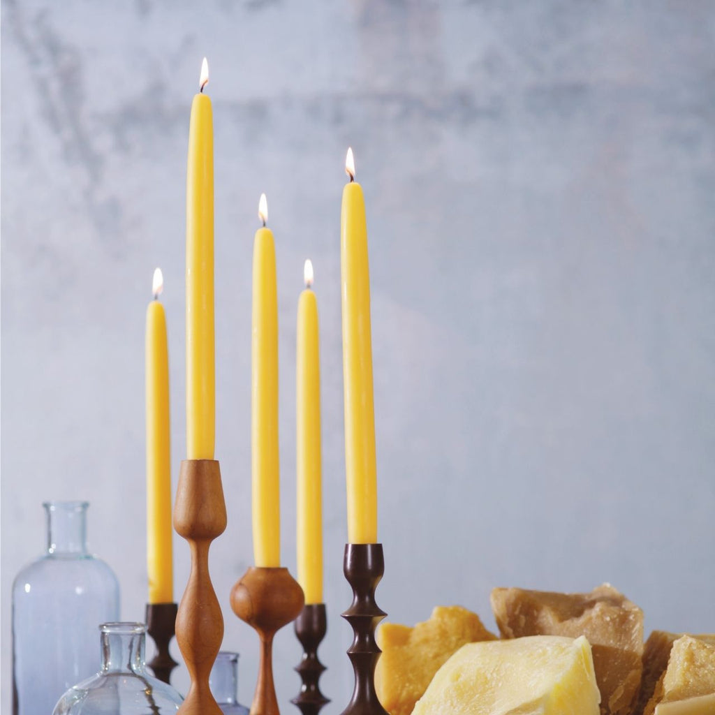 Yellow candles in wooden candlesticks with a neutral background