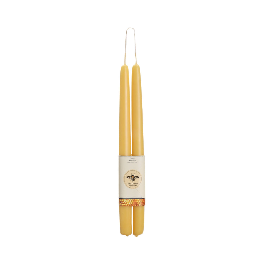 Two yellow candles with a label on a white background
