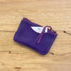 Purple leather cardholder on a wooden surface