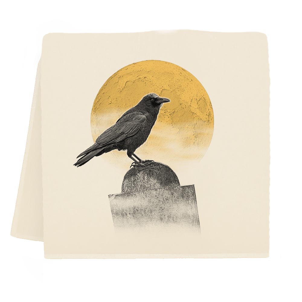 A square cream-colored tea towel, featuring a graphic print of a black raven perched on a tombstone in front of a textured golden-yellow moon.