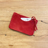Red leather cardholder with a card on a wooden surface