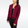 A woman wearing a cropped, long-sleeve western-style jacket in deep burgundy with contrast stitching, layered over a black top and black pants, against a light gray studio background.