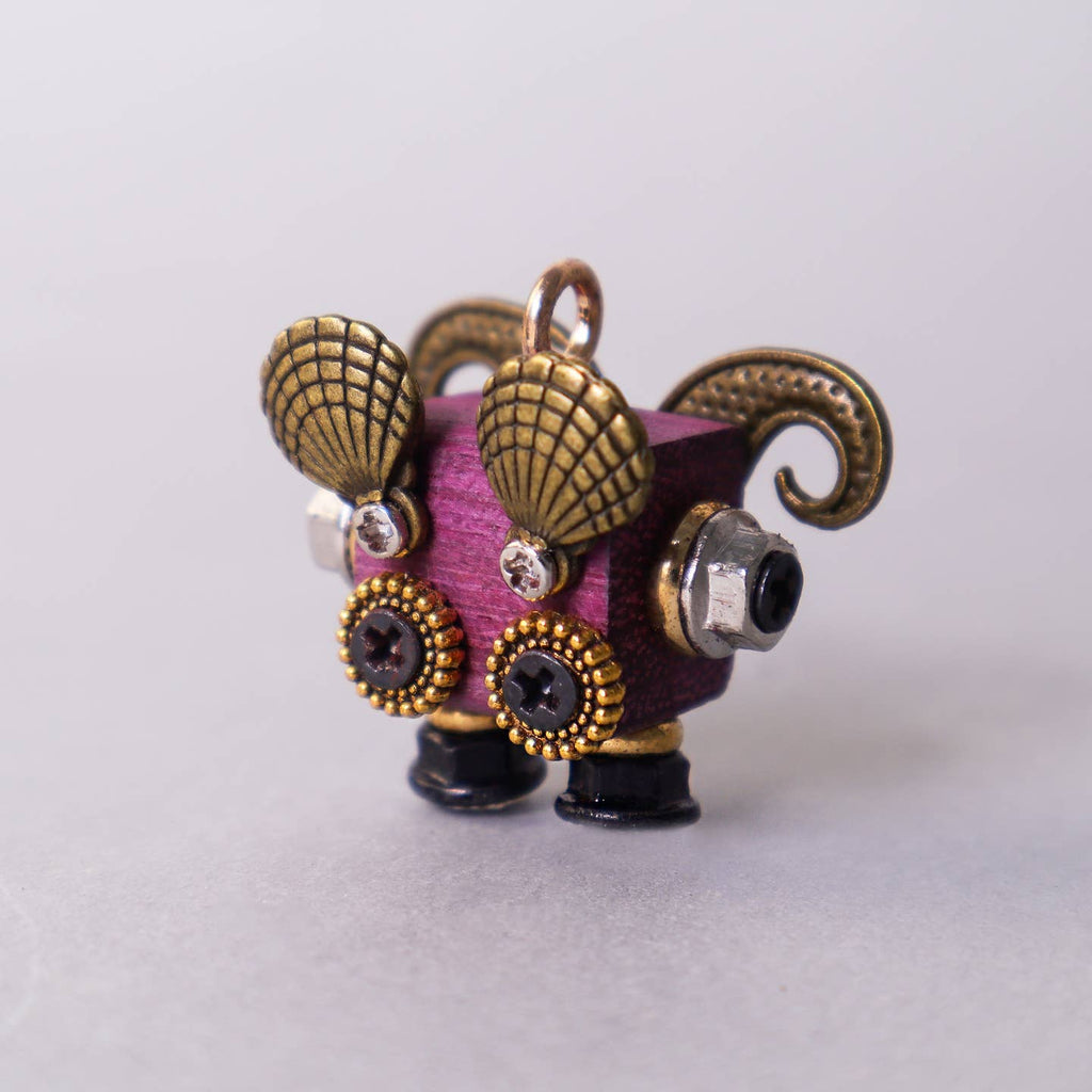 Small figurine with gold horns and decorative elements on a light gray background