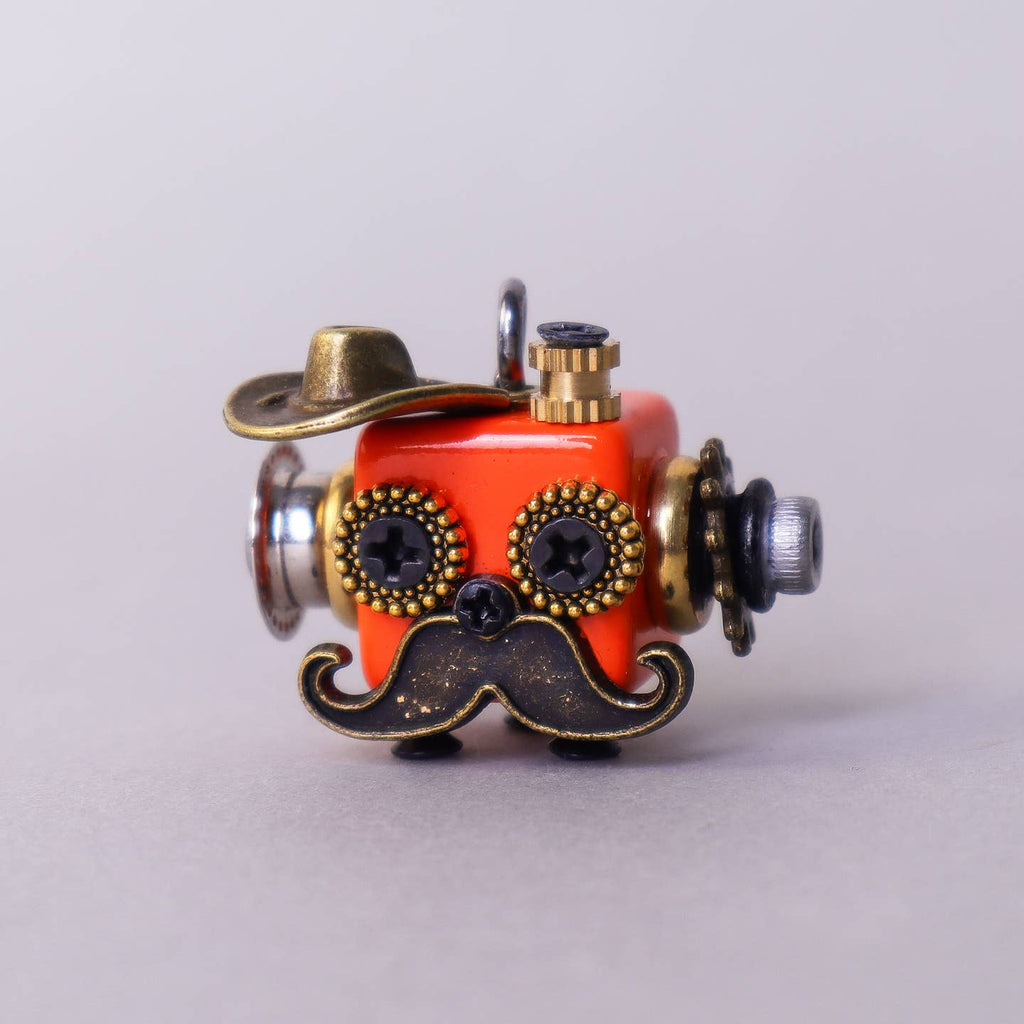 Small mechanical object with a red face, gold accents, and a mustache on a light gray background