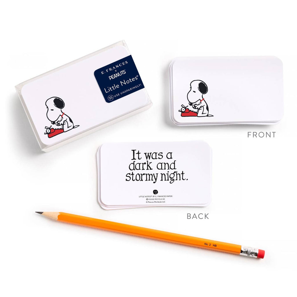 A set of white rectangular cards featuring the Peanuts character Snoopy, shown with front and back views on a white background, alongside a yellow pencil. One card reads 'It was a dark and stormy night.