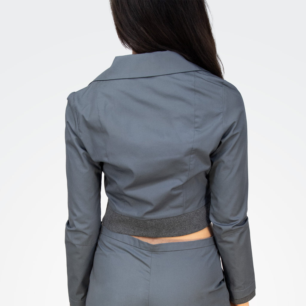 Person wearing a gray jacket and pants set on a white background