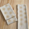Two folded napkins with sun pattern on a wooden surface