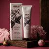 Formulary 55 Vintage Peony shea butter hand & body crème with packaging on a pink background with flowers.