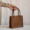 Brown bag being held in a hand with white background