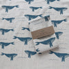 Folded towel on a opened up white towel with blue whale patterns